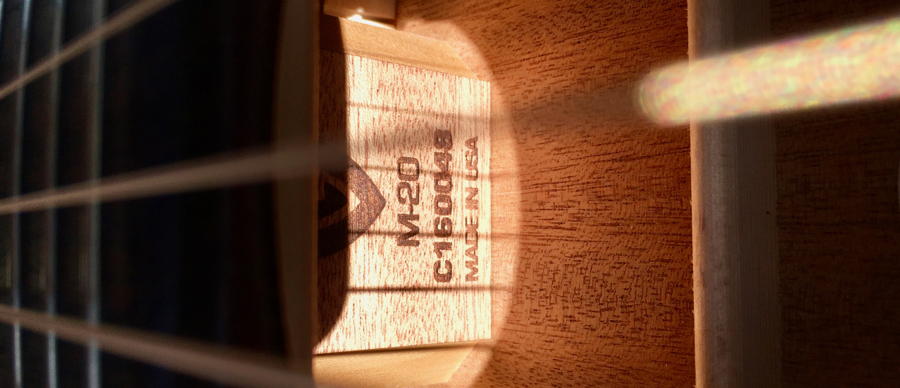 Looking in the sound hole of the guitar to see the serial number. 